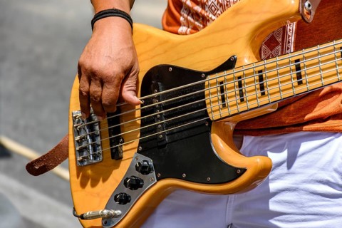 Hands playing an electric bass guitar on the street in a sunny day, Minas Gerais, Brazil, South