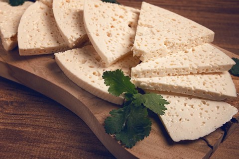 Sliced Georgian cheese, factory grade, on a wooden board, top view