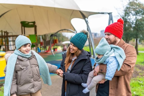 Smiling family bundled in warm winter clothes, enjoying a joyful day together at the playground,