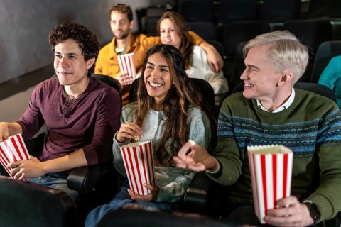 Happy friends enjoying a movie at the cinema, sharing popcorn, laughing, and creating unforgettable