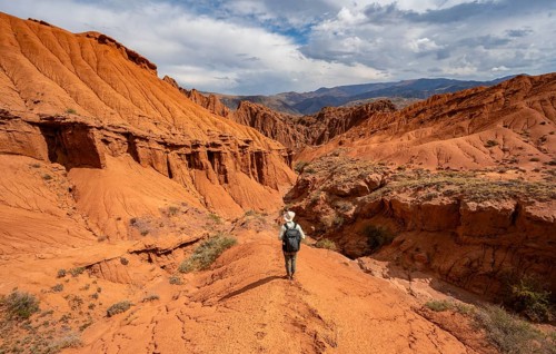 Mountaineer on a mountain ridge, view of eroded mountain landscape with sandstone cliffs, canyon