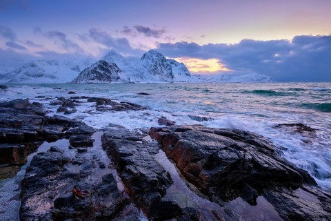 Beach of Norwegian sea on rocky coast in fjord on sunset in winter. Vareid beach, Lofoten islands,