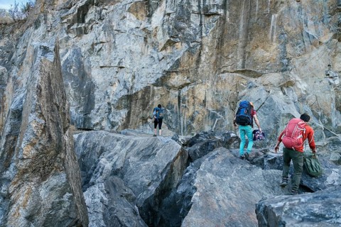 Climbers preparing for ascent. Three male female persons walking on the rocks. Extreme outdoor