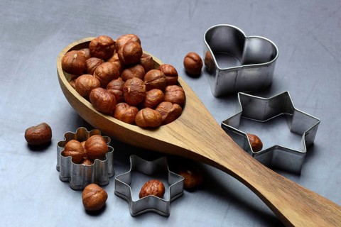 Wooden ladle with hazelnuts, cookie cutters, baking ingredient