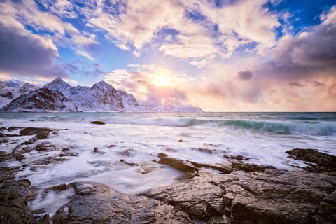 Beach of Norwegian sea on rocky coast in fjord on sunset in winter. Vareid beach, Lofoten islands,