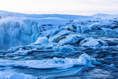 Icefall at the edge of the Godafoss waterfall at dawn, snow-covered landscape, Northern Iceland