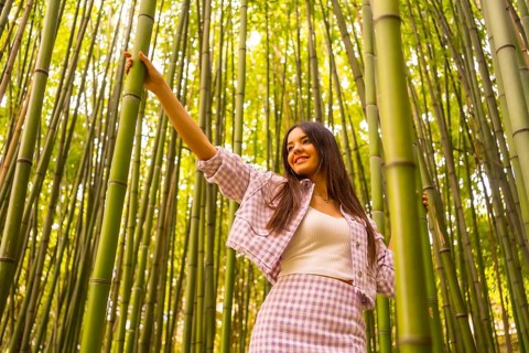 Young caucasian girl with a pink skirt in a bamboo forest. Enjoying the summer holidays in a
