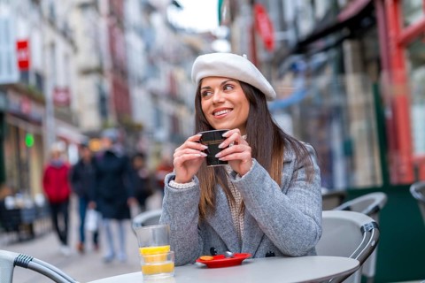 French style woman smiling looking away sitting in an outdoor cafeteria
