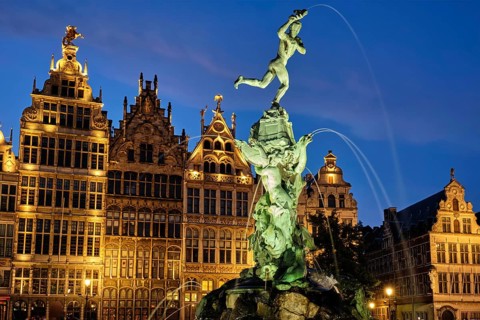Antwerp famous Brabo statue and fountain on Grote Markt square illuminated at night and old houses.