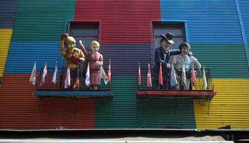 Colourful house facades with balconies and figures, decorated with flags, La Boca district, Buenos