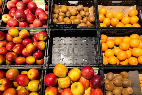Fruit counter in a supermarket or organic food shop, here with different types of apples, kiwis,