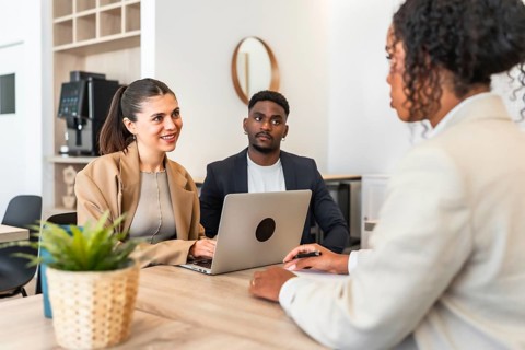 Business partners discussing with consultant using laptop during meeting in modern office