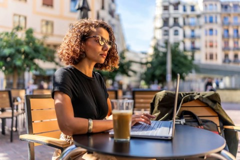 Side view of a beauty confident arab businesswoman working with laptop and drinking coffee outdoors