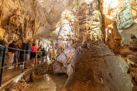 Tourists observing the magnificent stalactites and stalagmites formations inside postojna cave, a