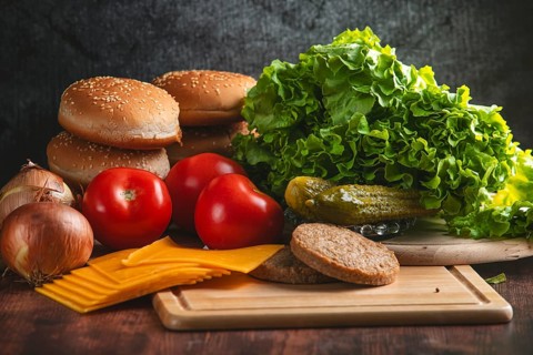 Fresh ingredients for a hamburger, such as lettuce, tomatoes, cheese and bun
