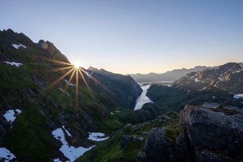 Picturesque mountain landscape at sunrise with sun star, fjord Trollfjord and Raftsund, hike to