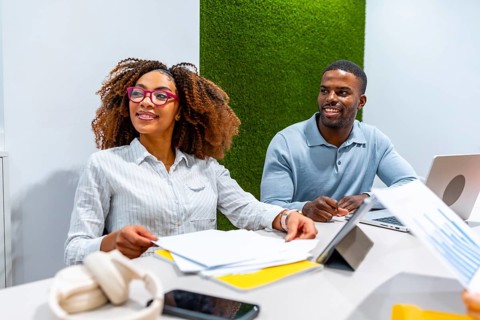 Two managers are cooperating in a modern coworking office, analyzing financial reports and