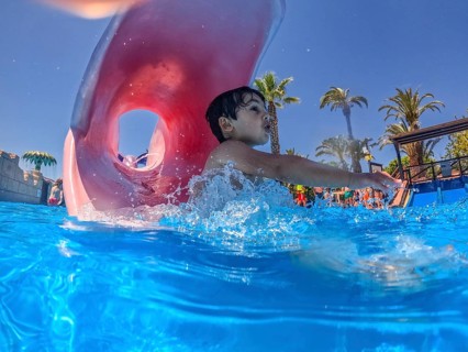 Young boy sliding joyfully into a pool at a vibrant water park, delighting in the excitement of