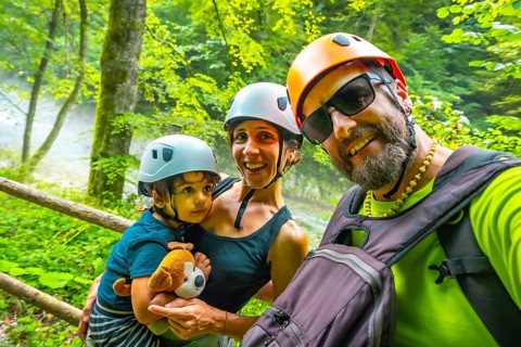 Smiling family wearing helmets taking a selfie while hiking in the beautiful vintgar gorge near