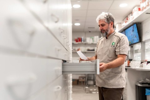 Side view of a male mature pharmacist looking for medicines in the storage room of a store