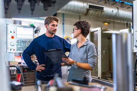 Male engineer and female manager doing inventory and talking in a factory