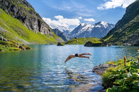 Man taking a header, cooling off while swimming in the mountain lake Lac de Louvie, behind the
