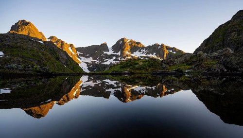 Rocky mountain peaks reflected in a small pond, mountain landscape with alpenglow at sunrise, at