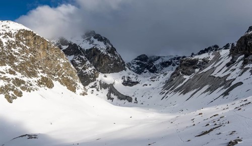 High mountain valley with mountain peak Piz Calderas in winter, view at the Chamanna Jenatsch in
