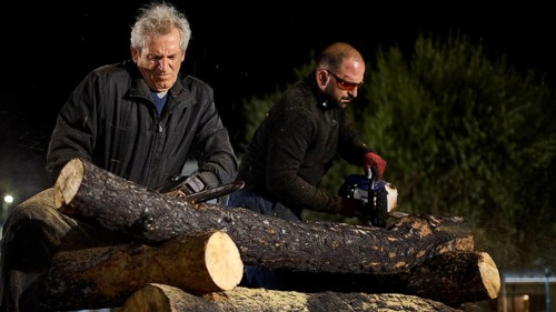 ©Udo Rein, Two men cutting thick logs with a chainsaw at night, Easter fire Psinthos, Holy