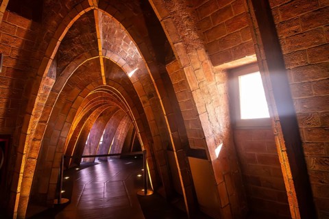 Warm sunlight streams through a window, illuminating the unique brick arches in the attic of casa