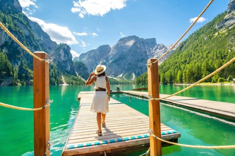 Woman walking along a wooden pier at lake braies, enjoying the turquoise waters and stunning