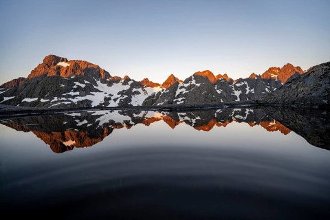 Rocky mountain peaks reflected in a small pond, mountain landscape with alpenglow at sunrise, at