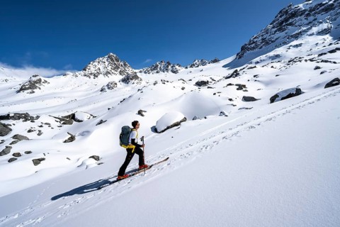 Ski tourers ascending through a picturesque snow-covered mountain landscape with peaks, ascent to
