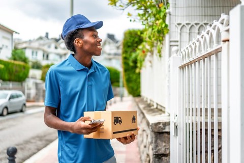 Delivery man using mobile to check the location holding a parcel