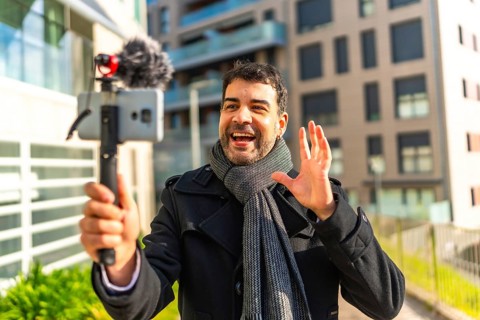 Male caucasian elegant mature vlogger waving while explaining something to the audience streaming