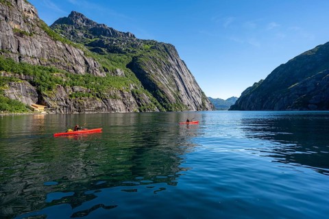Two kayakers with red kayaks in the fjord Trollfjord, mountains reflected in the water, fjord