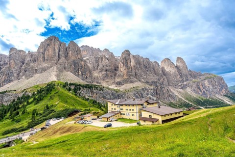 Green meadows and a mountain hotel are surrounded by the breathtaking peaks of the dolomites on a