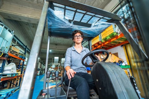 Frontal low angle view of a caucasian woman working in metallurgic factory driving a forklift