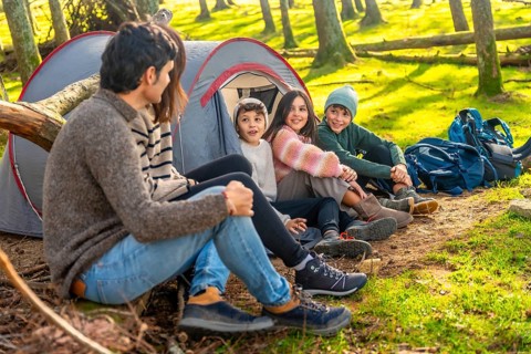 Caucasian family with three child enjoying a weekend camping in the forest together