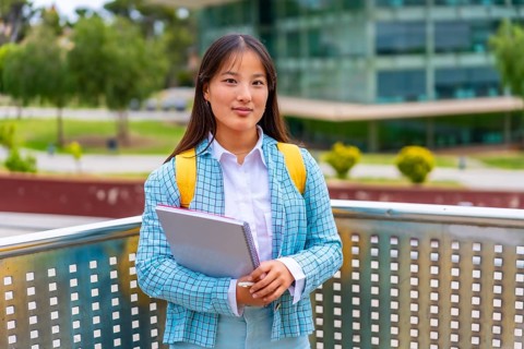 Three quarter length portrait of a beauty female asian student standing proud outside the