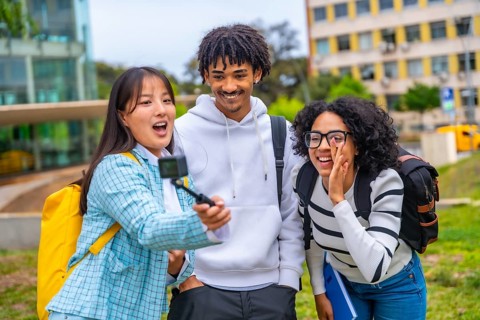 Three cool multi-ethnic students talking selfie with wearable camera and tripod