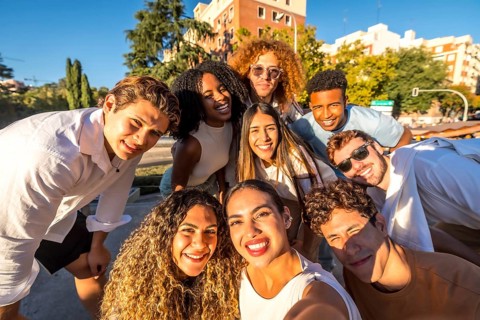Frontal view of a group of diverse young people taking selfie in the street smiling at camera