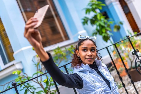 Urban stylish African american young woman taking selfie with cellphone in the city