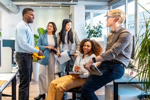 Diverse colleagues interacting, sharing ideas, and working together in a bright, open plan office