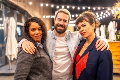 Portrait of three multi-ethnic friends embracing and smiling at camera at night party