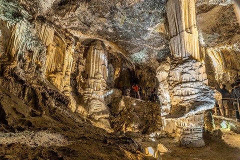 Tourists admiring giant stalactites and stalagmites inside the famous postojna cave, a major