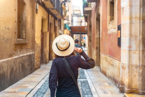 Tourist with straw hat walking in the medieval city of tarragona, spain, enjoying the historical