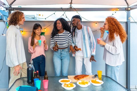 Multi-ethnic group of friends talking while celebrating party in the afternoon at rooftop