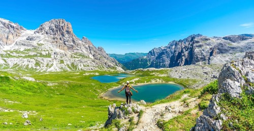 Tourist enjoying the scenic view of tre cime di lavaredo and alpine lakes on a sunny summer day in