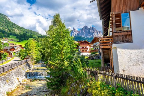 Scenic summer view of santa maddalena village with the odle mountains reflecting in the funes